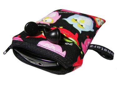 Schwarzes Stoffetui mit buntem Eulenmuster, Reißverschluss, Schlaufe, halb sichtbares Smartphone und In‑Ear‑Kopfhörer