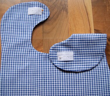 Zwei Babylätzchen-Schnittteile aus blau-weiß kariertem Stoff mit angeheftetem Klettverschluss