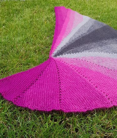 Halbrundes Stricktuch Magenta-Grau mit Lochmuster auf Gras
