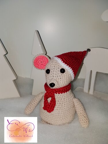 Gehäkelte Amigurumi-Maus in Creme mit roter Mütze und rotem Schal vor winterlicher Deko