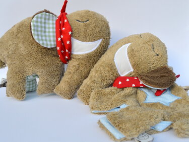 Nahaufnahme von Elefanten-Kuscheltieren mit applizierten Gesichtern, kontrastierenden Ohrenstoffen und roten Halstüchern.