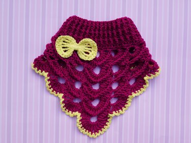 Magenta gehäkeltes Halstuch mit gelber Schleife und gelbem Wellenrand auf gestreiftem Hintergrund