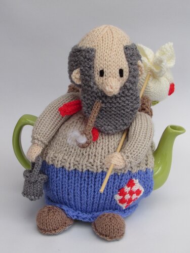 Knitted teapot cozy shaped like a bearded man with gray beard, beige sweater, blue lower body, red patch, and small accessories on a green teapot.