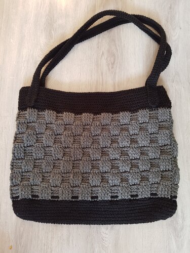 Gehäkelter schwarzer und grauer Shopper mit Korbmuster und langen Tragegurten auf hellem Boden