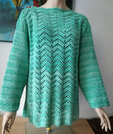 Türkisgrüner, gehäkelter Damenpullover mit Zickzack-Ajourmuster auf einer Schaufensterpuppe.