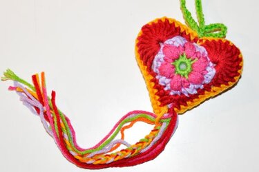 Bunt gehäkeltes Herz mit Blumenmotiv und mehrfarbiger Quaste