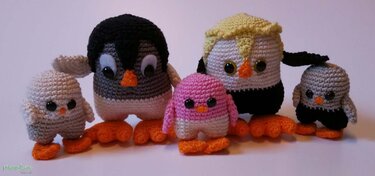 Fünf gehäkelte Amigurumi-Pinguine in verschiedenen Farben und Größen.