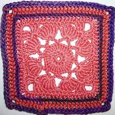 Gehäkeltes Granny-Quadrat mit Blumenmotiv, rosa Zentrum und lila Rand