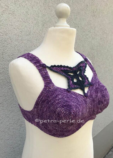Lila gehäkeltes Bustier mit schwarzem sternförmigem Ziermotiv auf Schaufensterpuppe