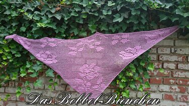 Lila gehäkeltes Dreieckstuch mit Blumen-Filetmuster, vor Backsteinmauer und Efeu drapiert