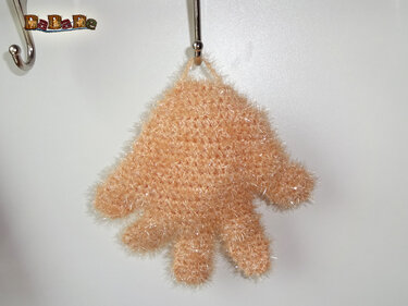 Pfirsichfarbener gehäkelter handförmiger Reinigungshandschuh mit Aufhängeschlaufe an Haken