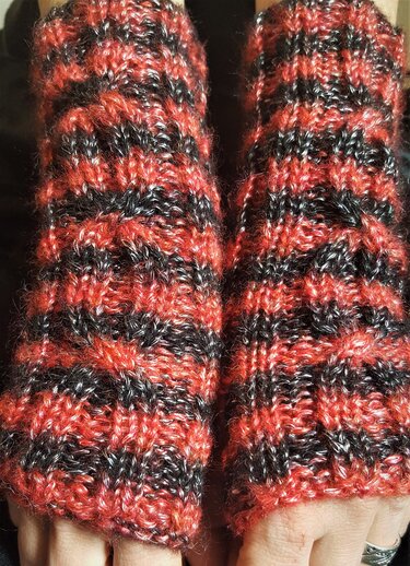 Fingerlose gestrickte Armstulpen in rot und schwarz gestreift an den Händen getragen