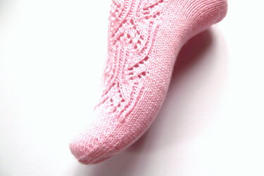 Rosa gestrickte Socke mit zartem Lochmuster auf weißem Hintergrund