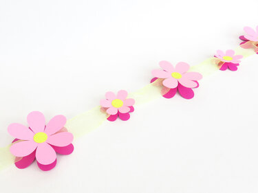 Girlande aus rosa Papierblumen auf hellem Band