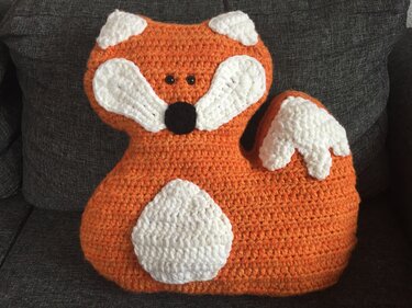Gehäkeltes Fuchskissen in Orange, Weiß und Schwarz auf grauem Sofa