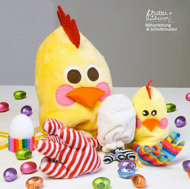 Zwei genähte gelbe Küken in groß und klein mit bunten Folien-Eiern auf weißer Fläche