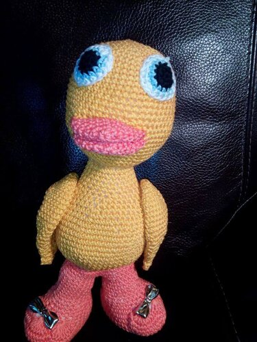 Gehäkeltes gelbes Vogel‑Amigurumi mit hellblauen Augenringen, rosa Schnabel und rosa Beinen