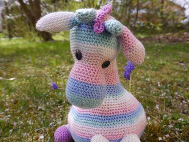 Nahaufnahme einer gehäkelten Giraffe: Maschenstruktur, Farbwechsel und Knopfaugen