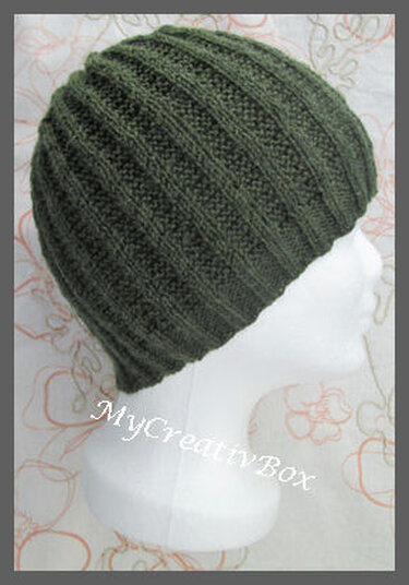 Dunkelgrüne Strickmütze mit Rippenmuster auf weißem Schaufensterkopf, Seitenansicht.