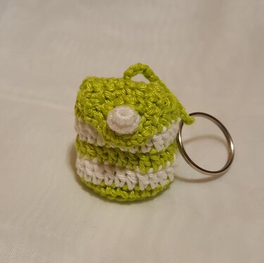 Gehäkelte Mini‑Tasche in limettengrün und weiß mit Knopfverschluss und Schlüsselring