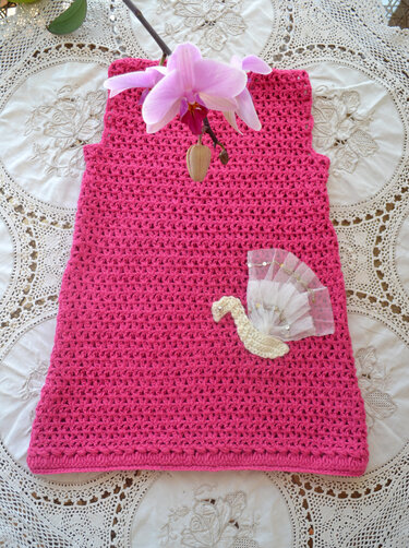 Ärmelloses pinkes gehäkeltes Kinderkleid mit Schwan-Applikation auf Spitzenunterlage