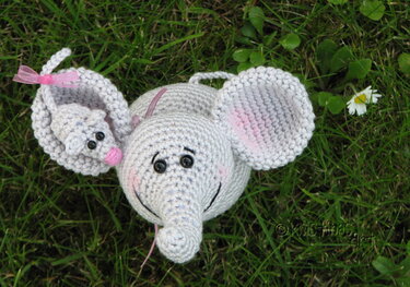 Handgehäkelter grauer Elefant und kleine Maus auf grüner Wiese mit Gänseblümchen