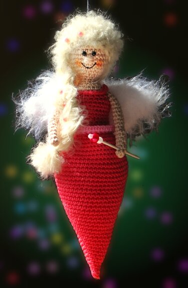 Gehäkelte Amigurumi-Fee in rotem Kleid mit blonden Haaren, weißen Flügeln und Zauberstab
