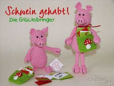 Zwei rosa gehäkelte Glücksschweine, eines stehend mit grüner Pilztasche, das andere sitzend