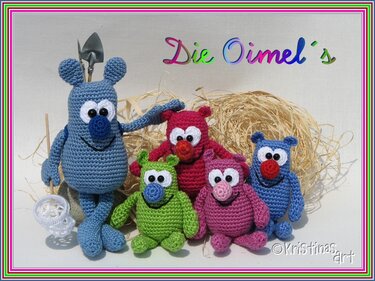 Fünf gehäkelte Amigurumi-Figuren in verschiedenen Farben vor Stroh