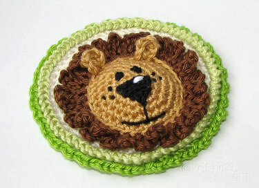 Runde gehäkelte Löwen-Applikation mit brauner Mähne und grünem Rand