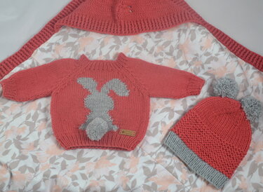 Gestricktes Baby-Set in Koralle und Grau mit Pullover (Hasenapplikation und Pompon), zweifarbiger Bommelmütze und Strickdecke.