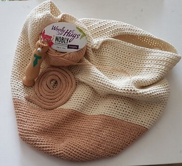 Gehäkelter Schulterrucksack in Creme und Beige mit Garnknäuel und Häkelnadel