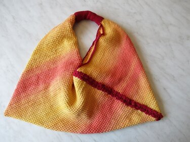 Gehäkelter Shopper mit Farbverlauf von Gelb über Orange zu Rot und dunkelroter Zierleiste
