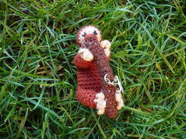 Gehäkelter Schnabeltier-Schlüsselanhänger mit Baumstamm auf Gras