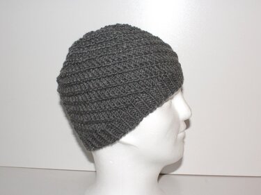 Seitliche Ansicht einer grauen gestrickten Beanie mit diagonaler Struktur auf einem weißen Schaufensterkopf
