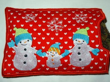 Rote rechteckige Stoffhülle mit drei bestickten Schneemännern, Herzmuster und Schneeflocken