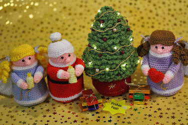 Gehäkelte Weihnachtsfiguren mit Tannenbaum, Weihnachtsmann, zwei Engeln und kleinen Geschenken vor goldenem Sternhintergrund