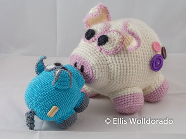 Gehäkeltes cremeweißes Schwein mit rosa Details und Knöpfen neben kleinem türkisfarbenem Amigurumi