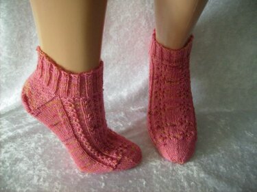 Rosa gestrickte Knöchelsocken mit Rippenbund und Lochmuster an Schaufensterpuppenbeinen