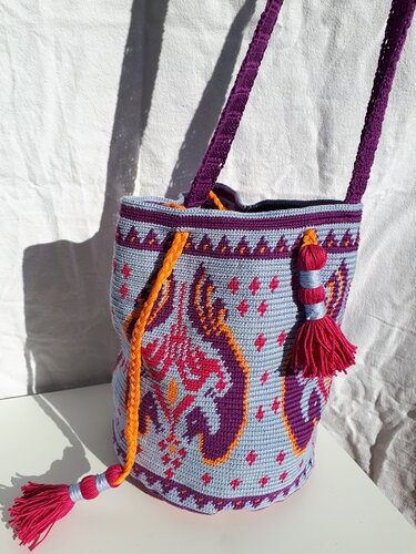 Gehäkelte Umhängetasche in Hellblau mit lila-pinken Ornamenten, orangefarbenem Tunnelzug und Quasten