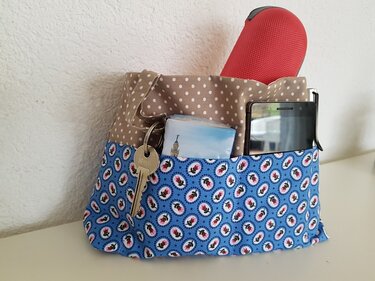 Stoff-Utensilo beige gepunktet und blau floral mit Außentaschen, darin Schlüssel und Handy