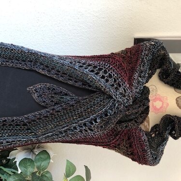 Gehäkeltes Tuch mit Lochmuster in Grau, Grün und Bordeaux auf dunklem Hintergrund