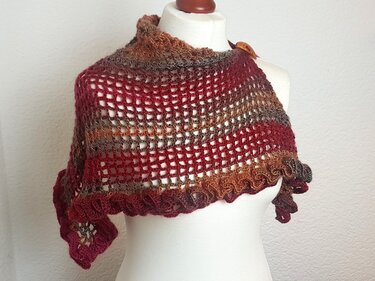 Gehäkeltes Dreieckstuch mit Farbverlauf, offenem Netzmuster und Rüschenrand auf einer Schneiderpuppe