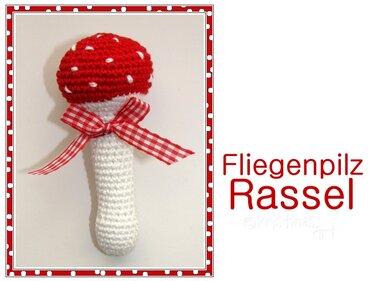Gehäkelte Fliegenpilz-Rassel mit roter Kappe, weißen Punkten und kariertem Band