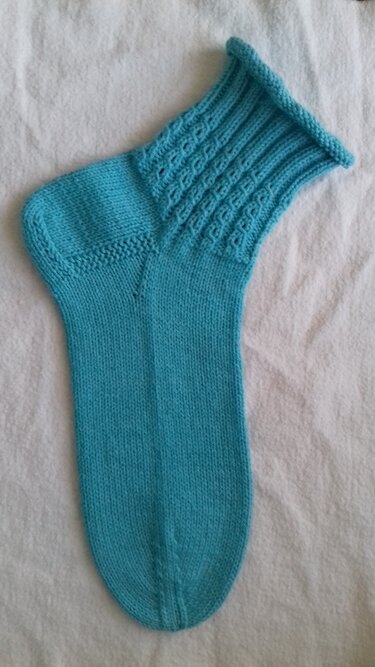 Handgestrickte türkise Damensocke mit strukturiertem Schaft auf hellem Hintergrund