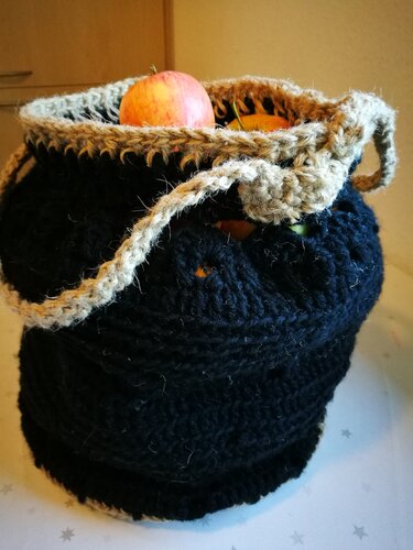 Schwarze gehäkelte Henkeltasche mit naturfarbenem Rand, gefüllt mit Äpfeln