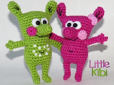 Zwei gehäkelte Amigurumi-Figuren in Grün und Pink mit großen Augen