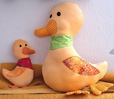 Große und kleine genähte Stoffenten mit farbigen Halstüchern und gemusterten Flügeln.