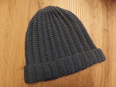 Gehäkelte graue Beanie mit Umschlag auf Holzuntergrund