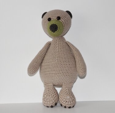 Gehäkelter beiger Amigurumi-Teddybär mit grüner Schnauze und schwarzen Knopfaugen